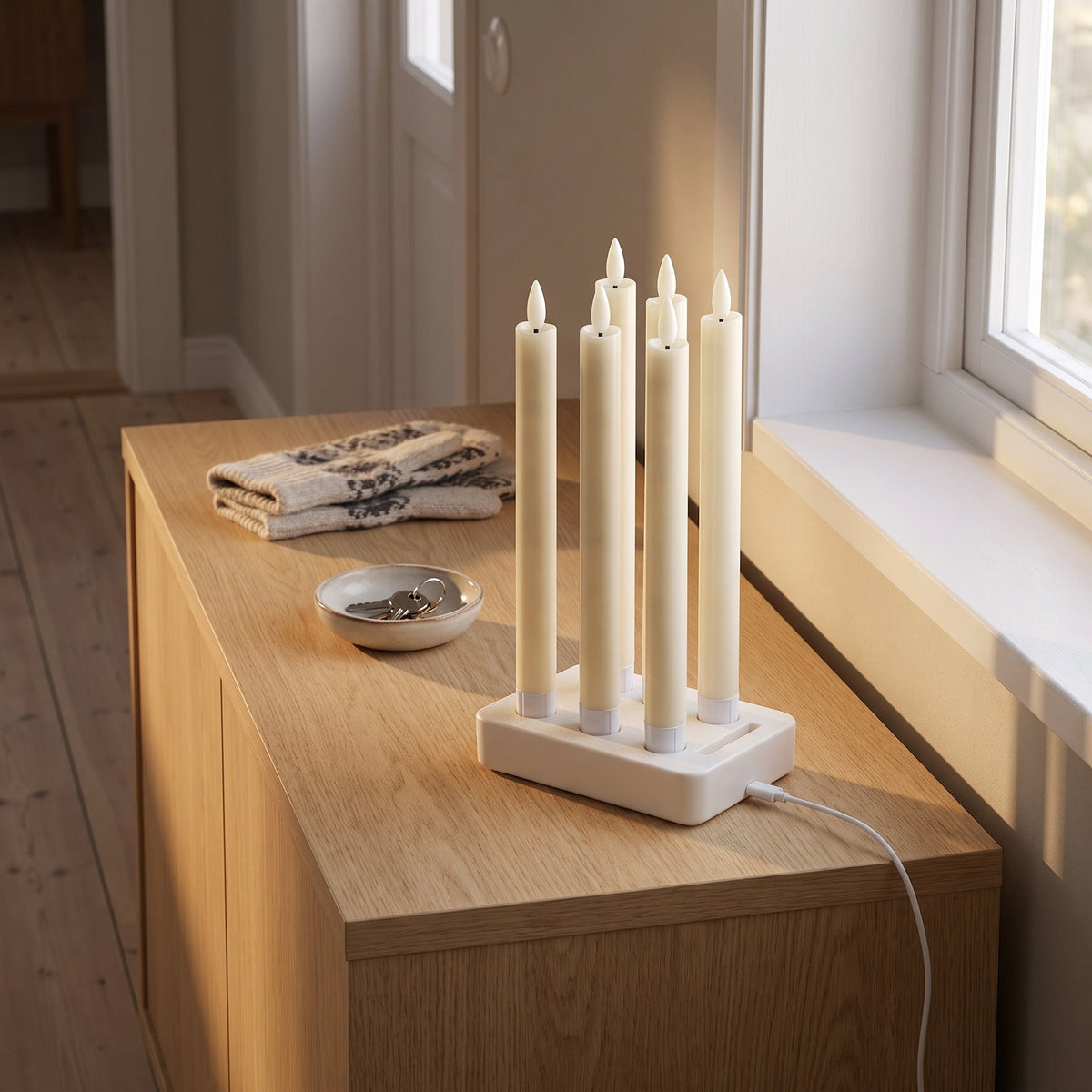 Le socle de charge de Flamélia avec les six bougies flambeaux, sur une commode de l'entrée, câble USB-C branché