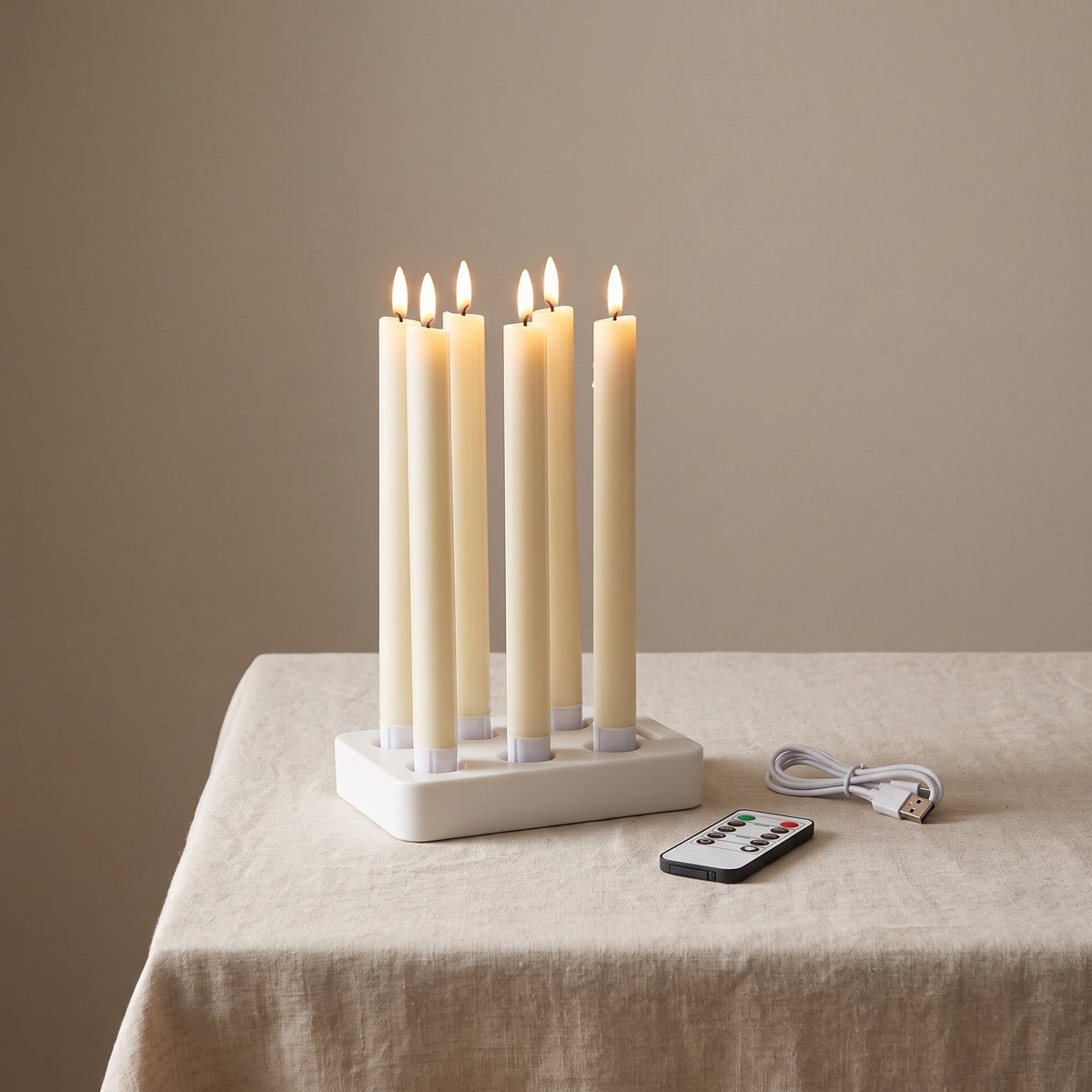 Le coffret complet : six bougies flambeaux Flamélia sur le socle de charge, avec la télécommande et le câble USB-C