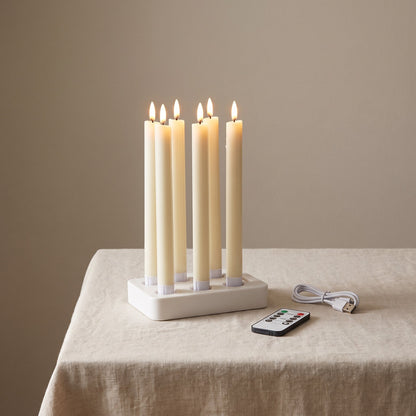 Le coffret complet : six bougies flambeaux Flamélia sur le socle de charge, avec la télécommande et le câble USB-C