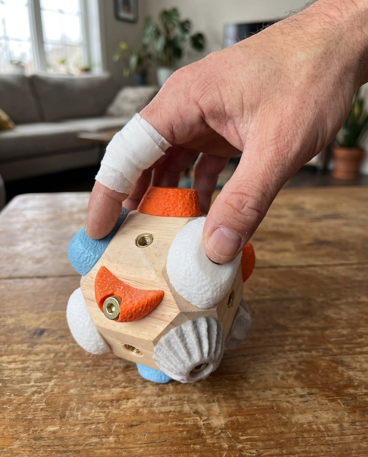 Une main de grimpeur avec un strap au doigt travaille doucement sur une prise du bloc