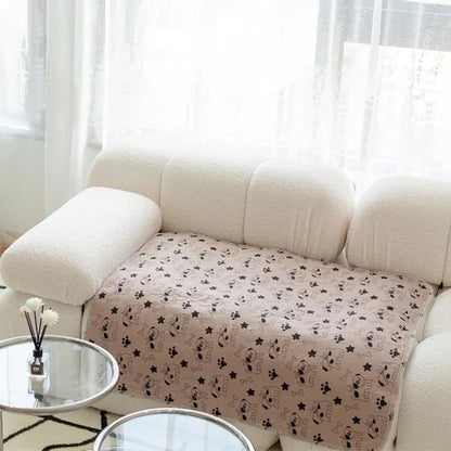 Tapis lavable Pattéa Sable à motif chiots posé sur un canapé blanc pour le protéger