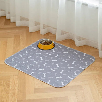 Tapis lavable Pattéa Gris à motif os sous une gamelle de croquettes, sur un parquet