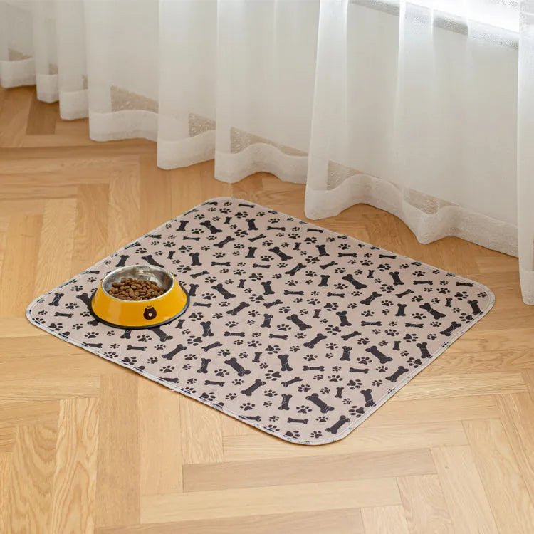 Tapis lavable Pattéa Beige à motif os et pattes sous une gamelle, sur un parquet